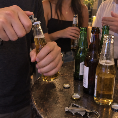 Iemand opent een flesje bier met de PermaVuur sleutelhanger