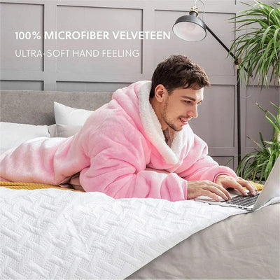 Man in een roze fleece hoodie-deken werkt op zijn laptop