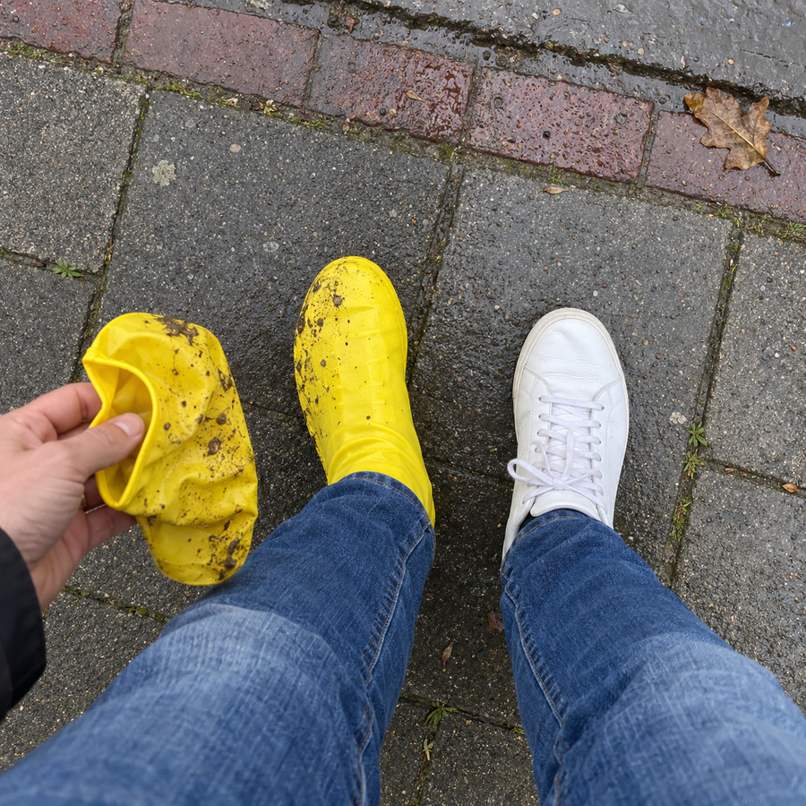 Een modderige gele overschoen is net uitgetrokken, de witte sneaker eronder is schoon gebleven